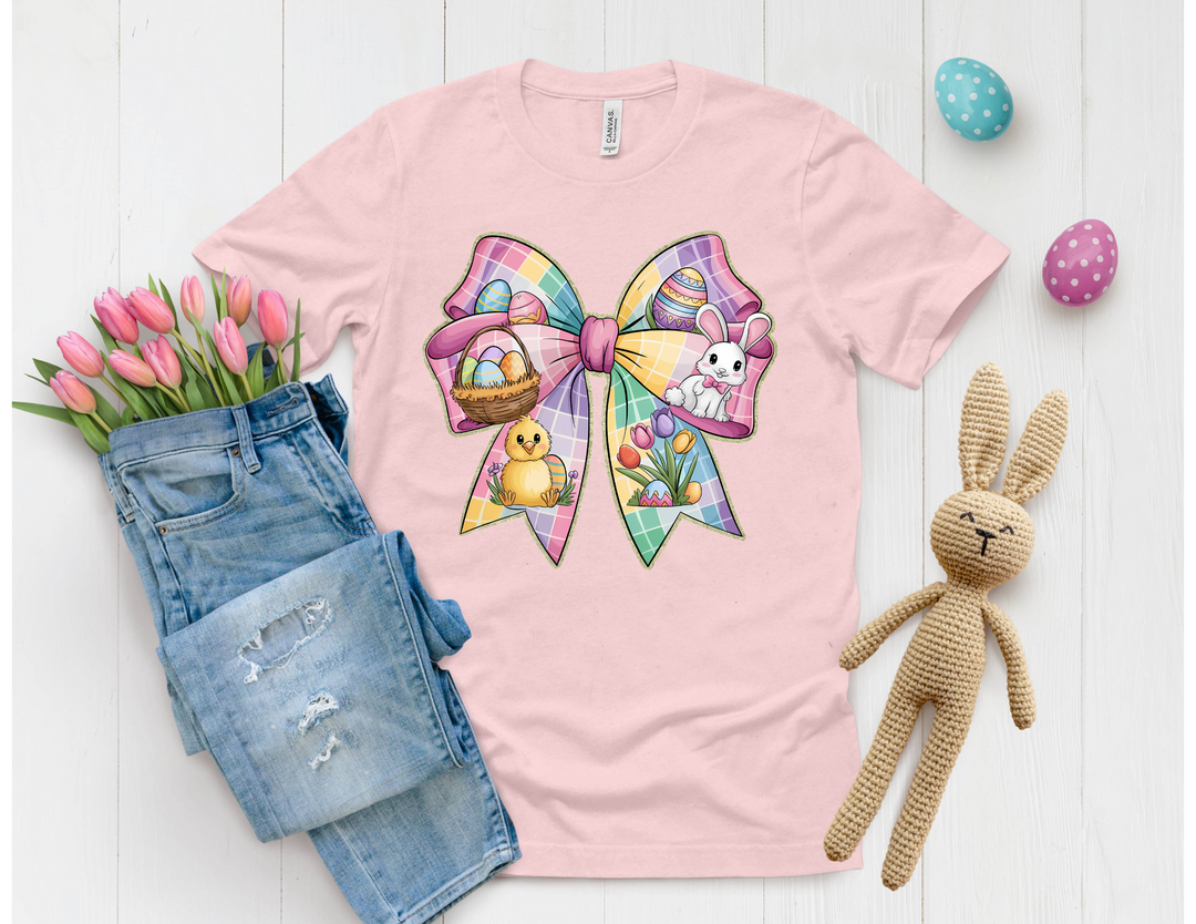 A pink shirt with a colorful bow design featuring Easter motifs, paired with distressed jeans, tulips, and a bunny plush toy